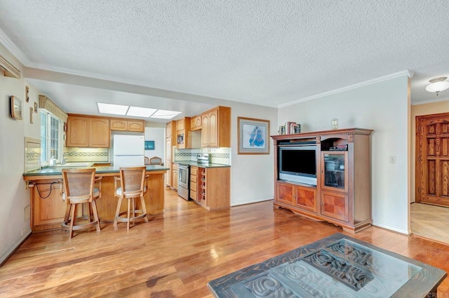 kitchen featuring a breakfast bar area, stainless steel electric range, light hardwood / wood-style flooring, kitchen peninsula, and white fridge