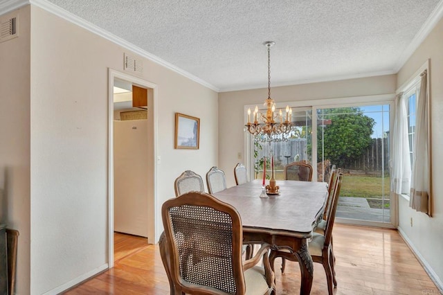 dining area with an inviting chandelier, ornamental molding, light hardwood / wood-style flooring, and a textured ceiling