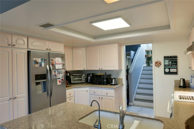 kitchen featuring sink, stainless steel fridge, range, white cabinets, and a raised ceiling