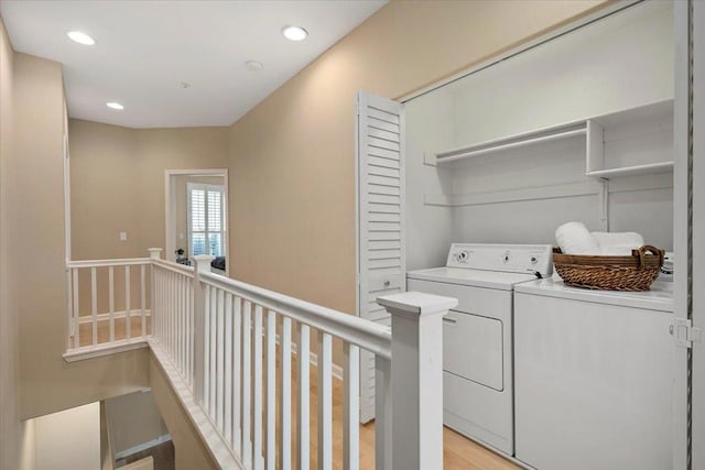 clothes washing area featuring independent washer and dryer and light hardwood / wood-style floors