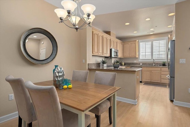 dining space with an inviting chandelier, sink, and light hardwood / wood-style flooring