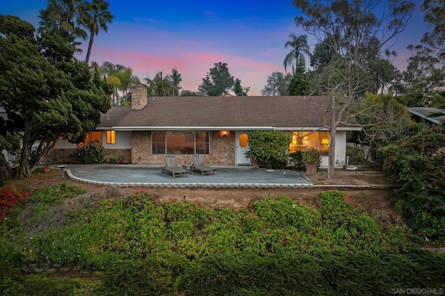 back house at dusk featuring a patio area