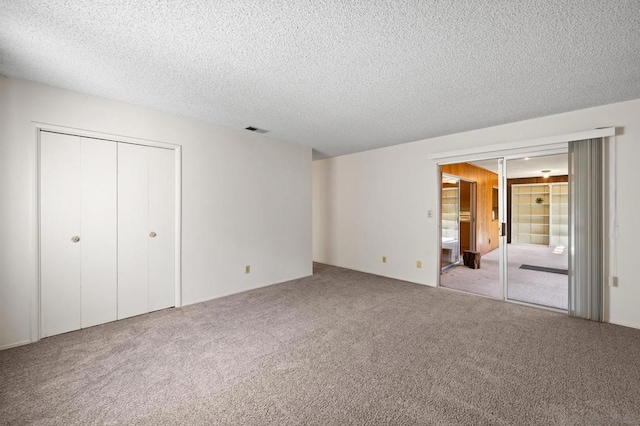 unfurnished bedroom with light colored carpet, a closet, and a textured ceiling