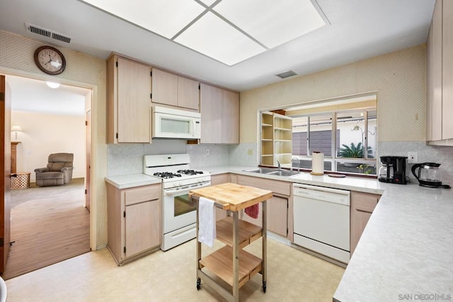 kitchen featuring sink, light brown cabinets, white appliances, and a skylight