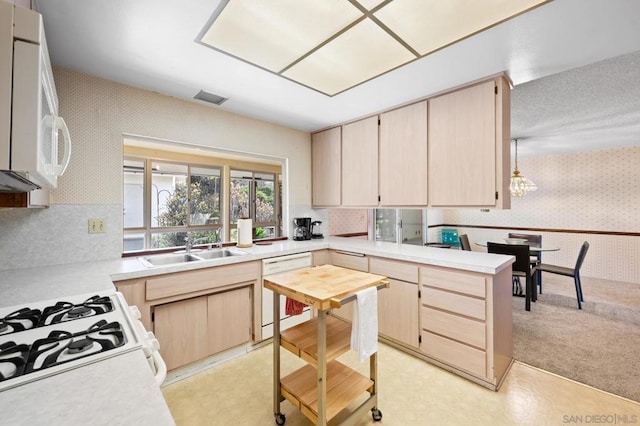 kitchen featuring light brown cabinetry, sink, light carpet, kitchen peninsula, and white appliances