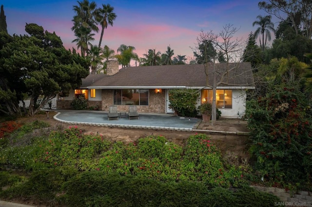 back house at dusk with a patio