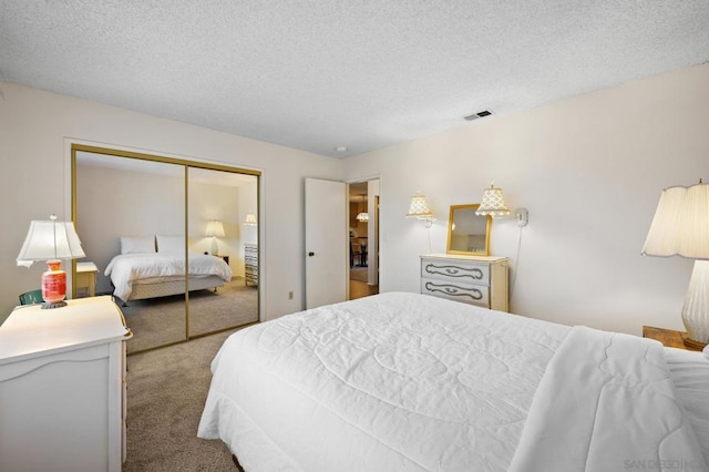 carpeted bedroom with a closet and a textured ceiling