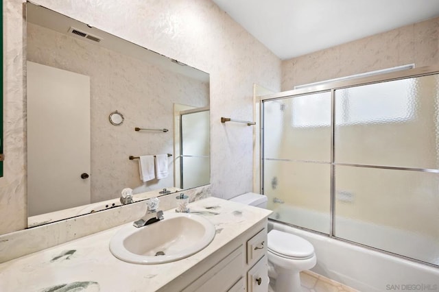 full bathroom featuring vanity, bath / shower combo with glass door, and toilet