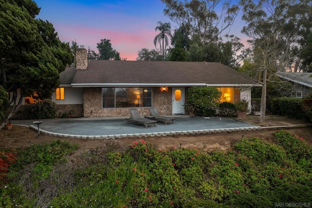 back house at dusk featuring a patio