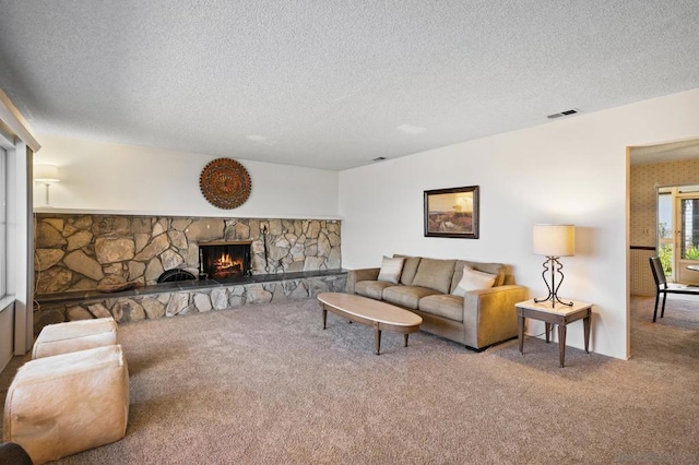 living room with a stone fireplace, carpet floors, and a textured ceiling