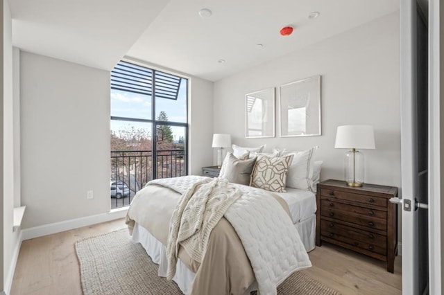 bedroom featuring floor to ceiling windows, access to outside, and light wood-type flooring