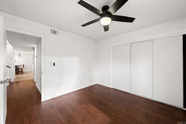 unfurnished bedroom featuring a closet, dark hardwood / wood-style floors, and ceiling fan