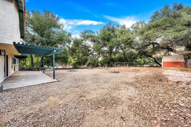 view of yard with a shed, a pergola, and an outdoor fire pit