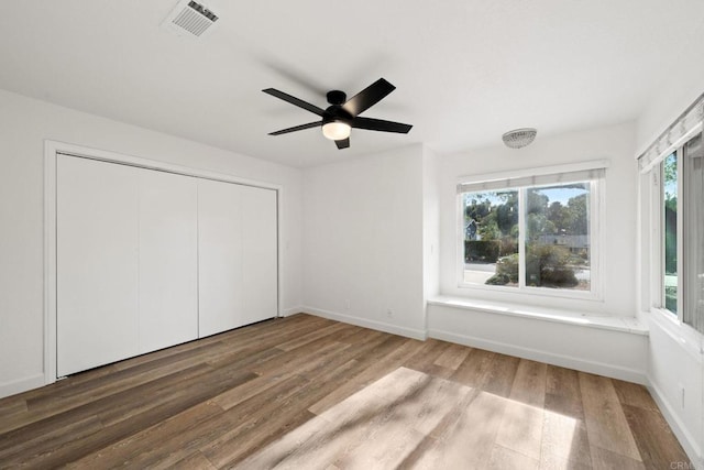 unfurnished bedroom featuring hardwood / wood-style floors, a closet, and ceiling fan