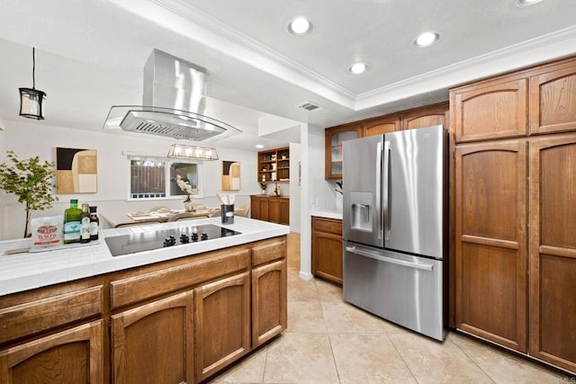 kitchen featuring crown molding, black electric stovetop, island range hood, a tray ceiling, and stainless steel fridge with ice dispenser