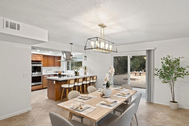 tiled dining space with a chandelier and a textured ceiling