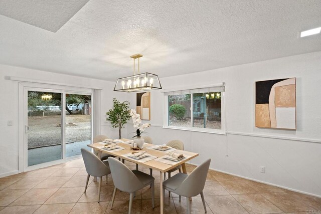 tiled dining space featuring a notable chandelier and a textured ceiling