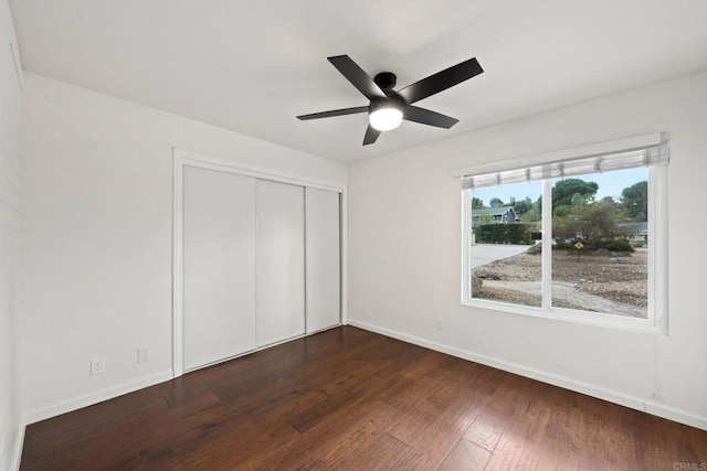 unfurnished bedroom with ceiling fan, dark hardwood / wood-style floors, and a closet