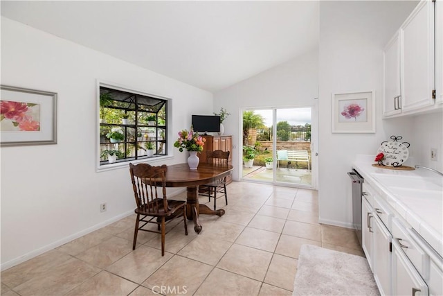 dining space with lofted ceiling, sink, and light tile patterned floors