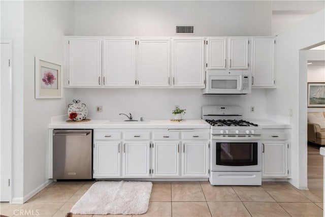 kitchen featuring white appliances, light tile patterned floors, sink, and white cabinets