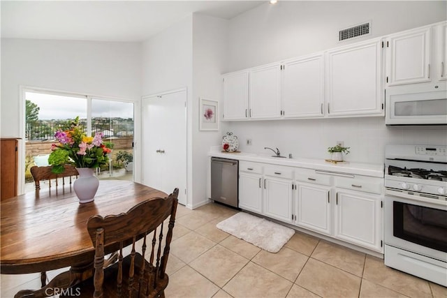 kitchen featuring light tile patterned floors, white appliances, sink, white cabinetry, and backsplash