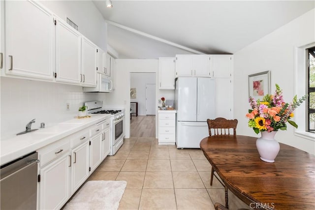 kitchen with lofted ceiling, sink, white cabinets, light tile patterned floors, and white appliances