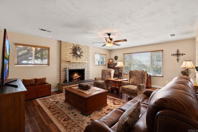 living room featuring a fireplace, dark hardwood / wood-style flooring, a textured ceiling, and a wealth of natural light