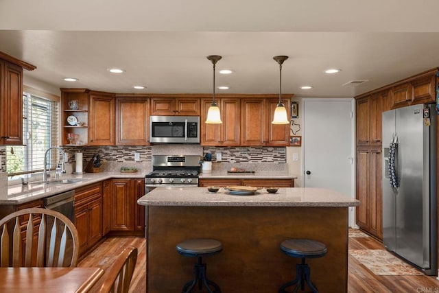 kitchen featuring sink, decorative light fixtures, a center island, stainless steel appliances, and light hardwood / wood-style floors