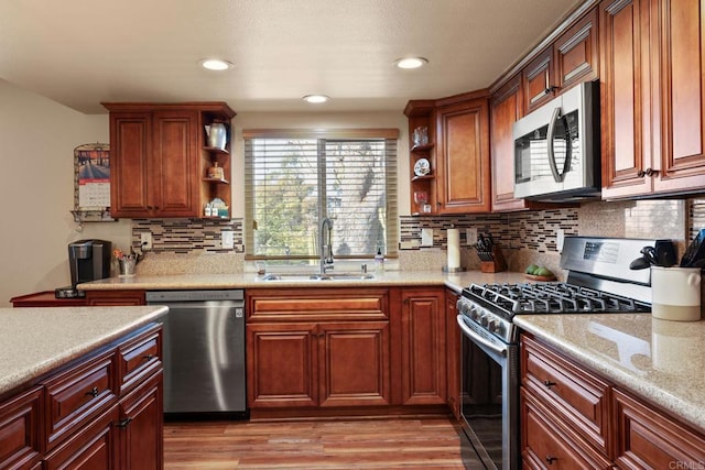 kitchen featuring sink, appliances with stainless steel finishes, backsplash, light hardwood / wood-style floors, and light stone countertops