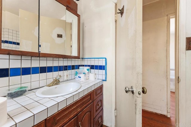 bathroom with hardwood / wood-style flooring, vanity, and backsplash