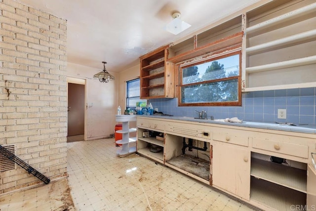 kitchen featuring backsplash, decorative light fixtures, plenty of natural light, and sink