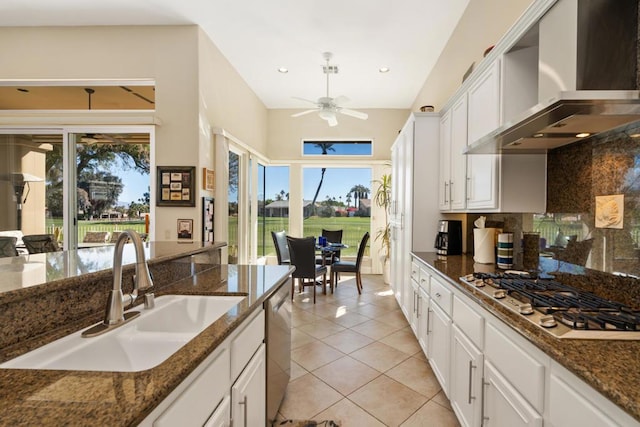 kitchen with sink, stainless steel appliances, white cabinets, dark stone counters, and wall chimney exhaust hood