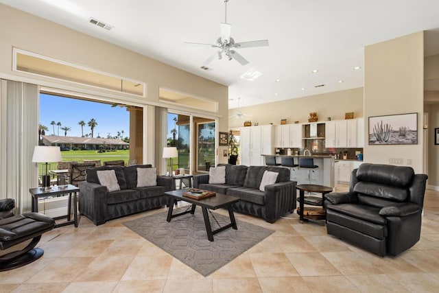 living room featuring ceiling fan, a towering ceiling, and light tile patterned floors