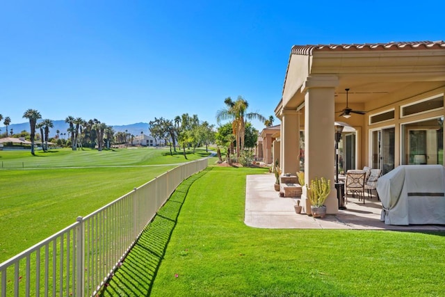 view of yard with ceiling fan, a mountain view, and a patio area