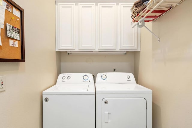 clothes washing area featuring cabinets and washer and clothes dryer