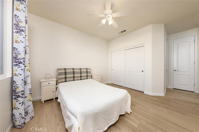 bedroom featuring ceiling fan, visible vents, baseboards, light wood-style floors, and a closet