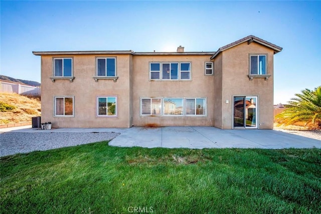 back of property featuring stucco siding, central AC, a lawn, and a patio