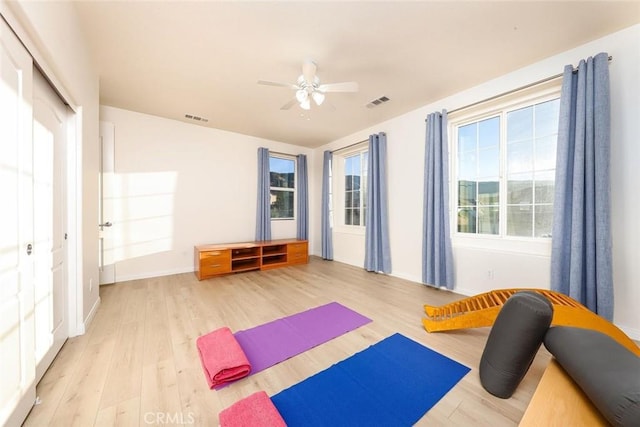 exercise room with light wood-type flooring, visible vents, and a ceiling fan