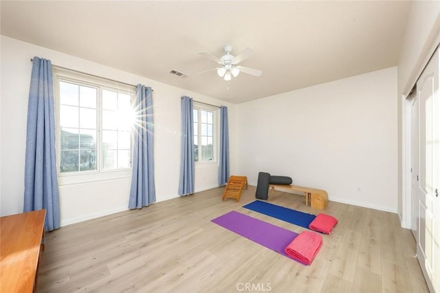 exercise room with ceiling fan, visible vents, and wood finished floors