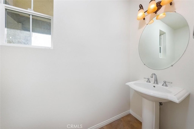 bathroom featuring a chandelier, a sink, and baseboards