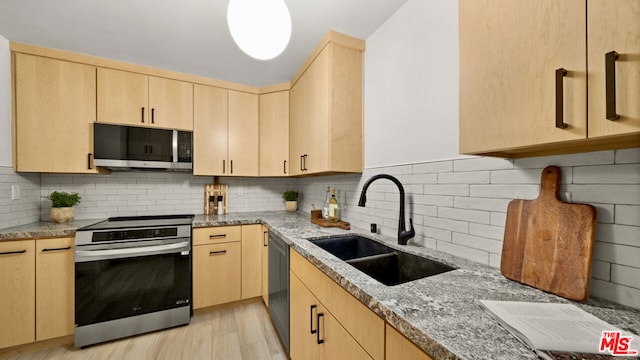 kitchen with light brown cabinetry, sink, appliances with stainless steel finishes, light stone countertops, and decorative backsplash