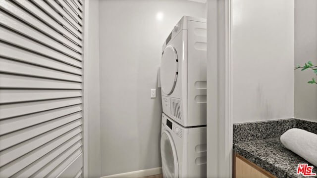 clothes washing area featuring stacked washing maching and dryer