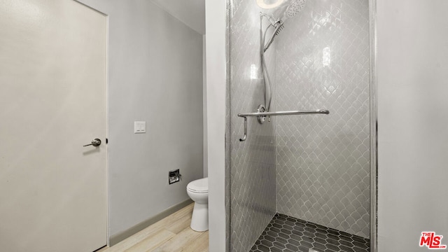 bathroom featuring tiled shower, hardwood / wood-style floors, and toilet