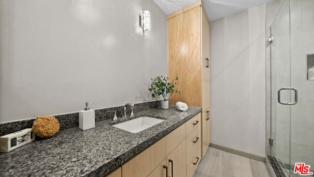 bathroom with walk in shower, vanity, and hardwood / wood-style floors