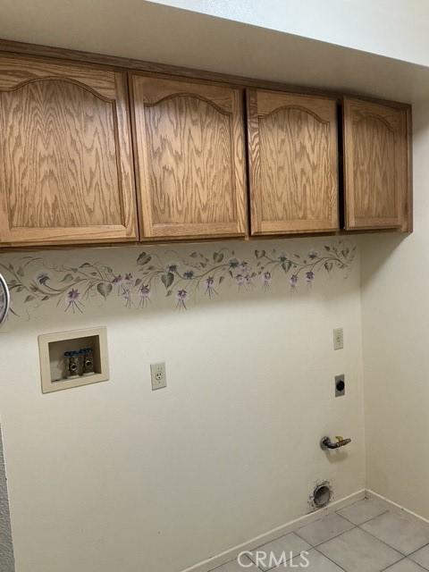 laundry room with gas dryer hookup, cabinets, light tile patterned floors, electric dryer hookup, and washer hookup