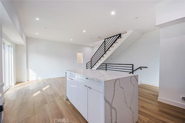 kitchen featuring white cabinetry, light stone counters, light hardwood / wood-style flooring, and a kitchen island