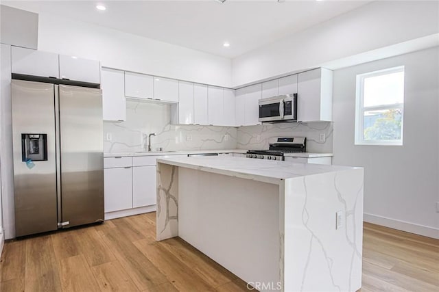 kitchen with white cabinetry, sink, a center island, light hardwood / wood-style floors, and stainless steel appliances