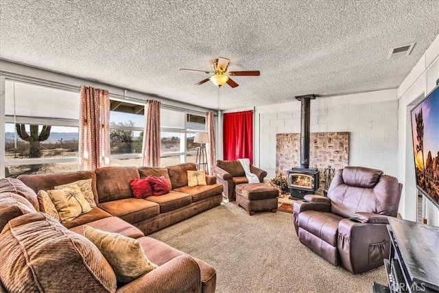 carpeted living room featuring ceiling fan, a textured ceiling, and a wood stove