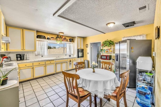 kitchen with tasteful backsplash, stainless steel fridge, oven, and light tile patterned floors