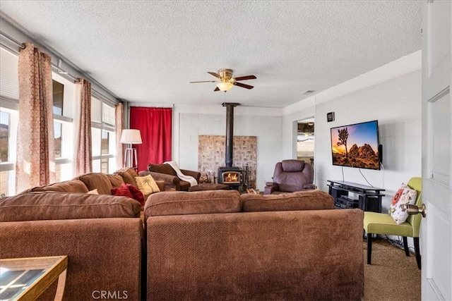 carpeted living room featuring ceiling fan, a wood stove, and a textured ceiling